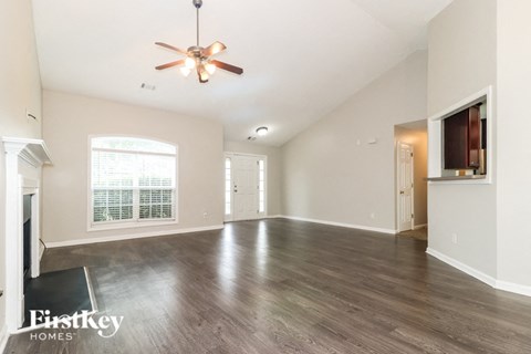 A spacious room with a ceiling fan and wooden flooring.