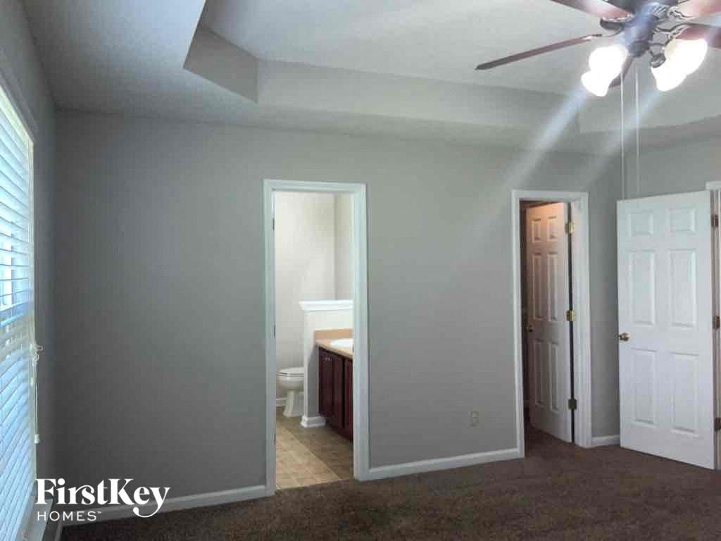 a bedroom with a ceiling fan and a bathroom with a toilet