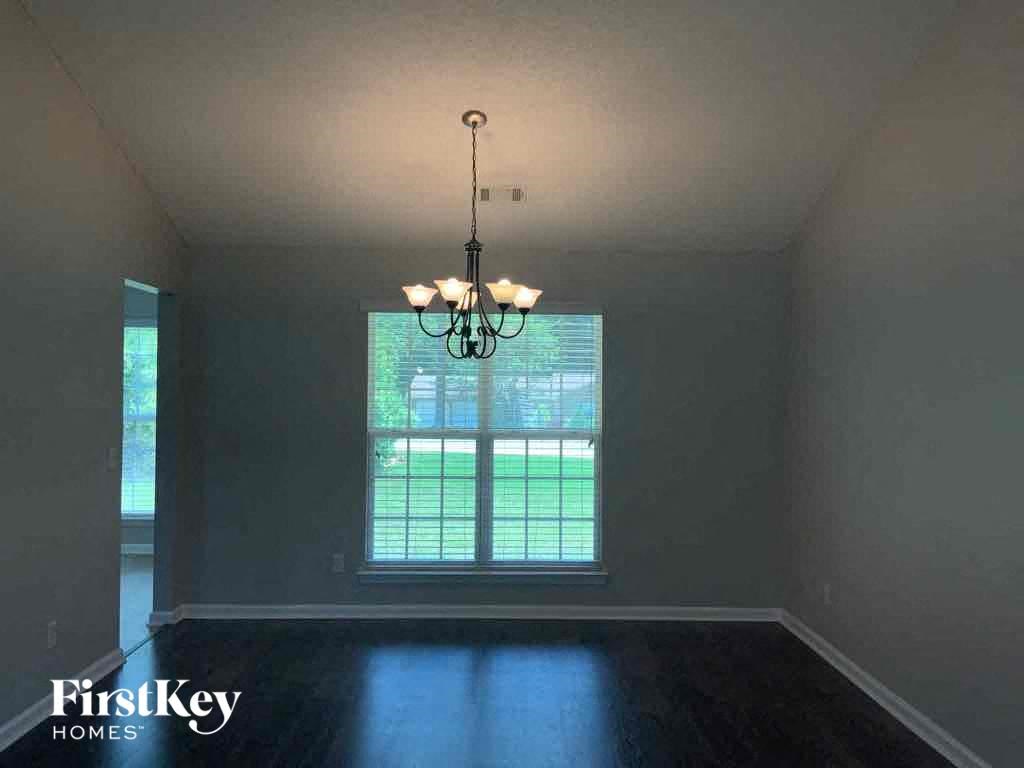 an empty living room with a large window and a chandelier
