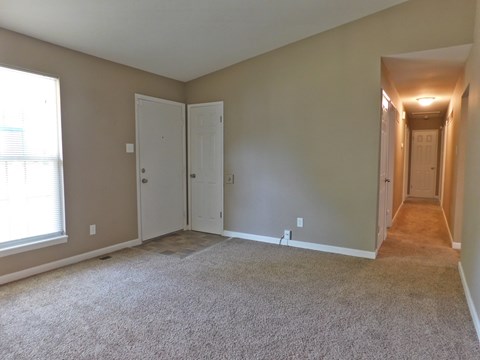 a bedroom with a carpeted floor and a door to a hallway