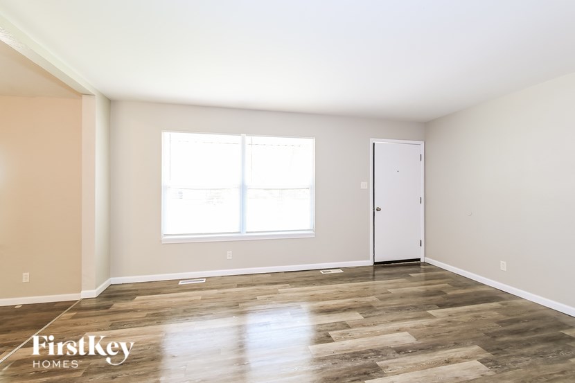 A room with wooden flooring and a white door is shown.