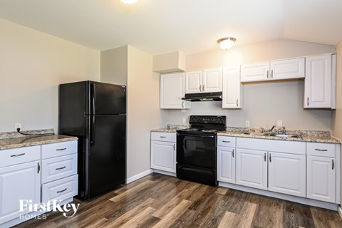 A kitchen with a black refrigerator and stove, and white cabinets.