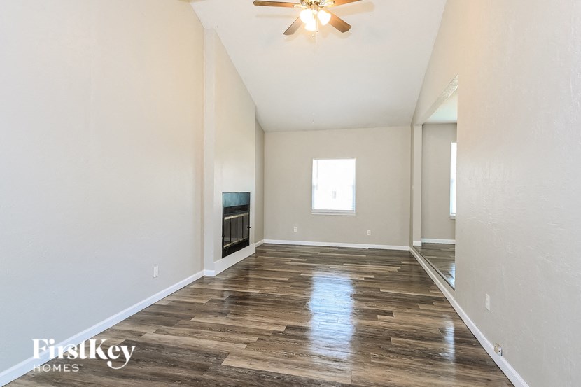 A spacious room with wooden flooring and a ceiling fan.