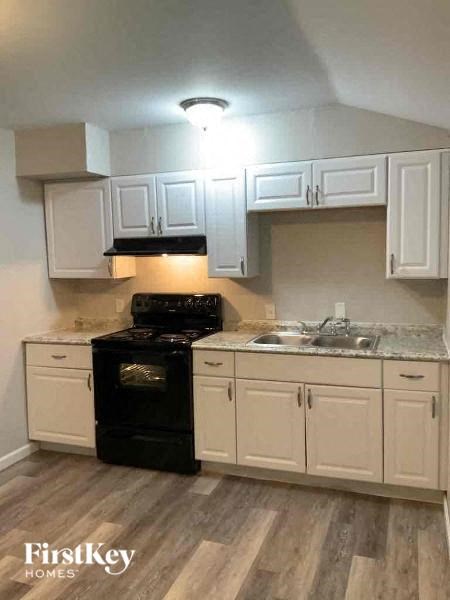 A kitchen with a black stove top oven and white cabinets.