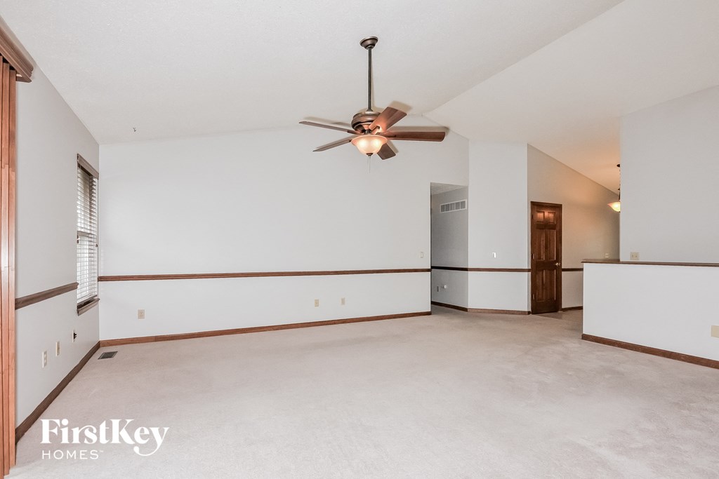 an empty living room with a ceiling fan and white walls