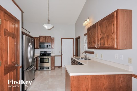 a kitchen with wooden cabinets and stainless steel appliances and a white counter top