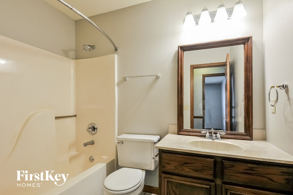 a bathroom with a toilet sink and shower and a mirror