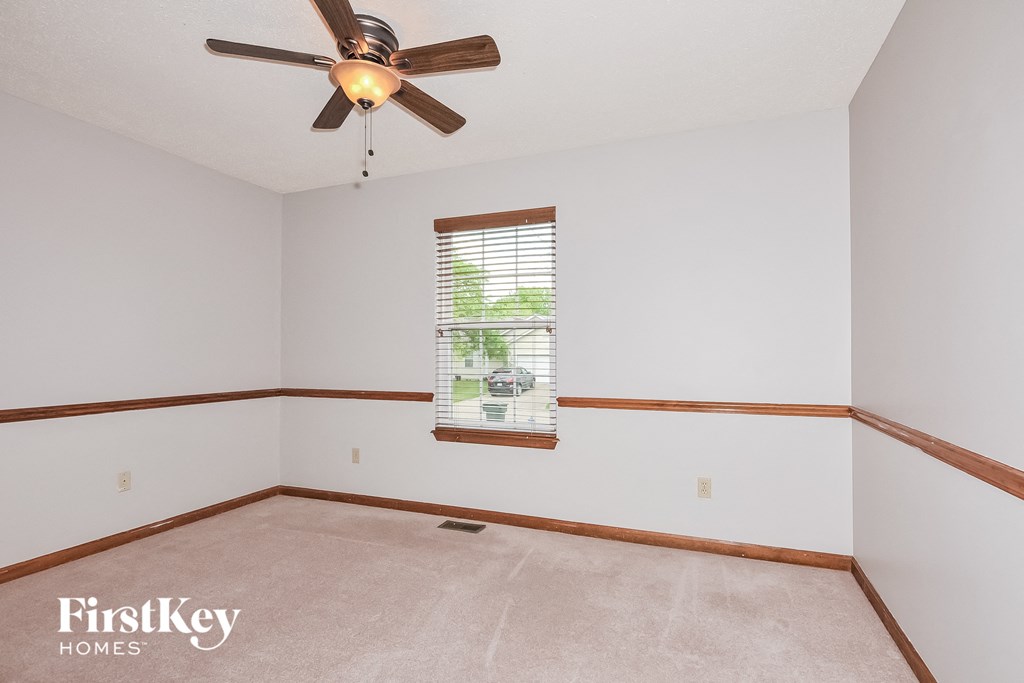 a bedroom with white walls and a ceiling fan and a window