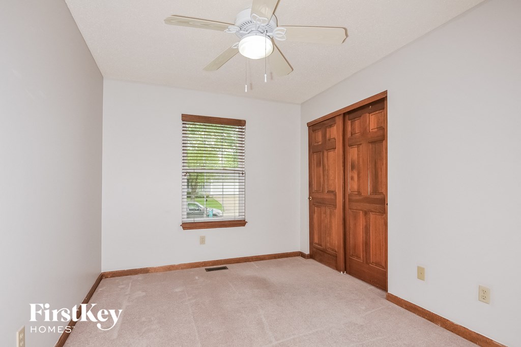 an empty room with a ceiling fan and a window