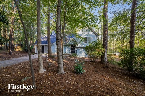 a blue house in the woods with trees