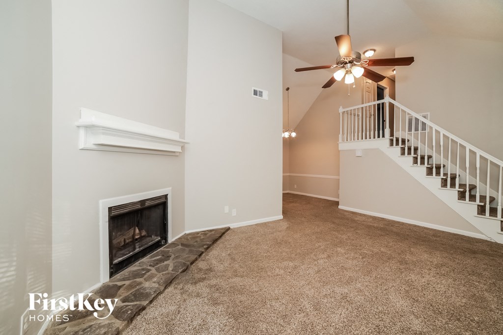 an empty living room with a fireplace and a staircase