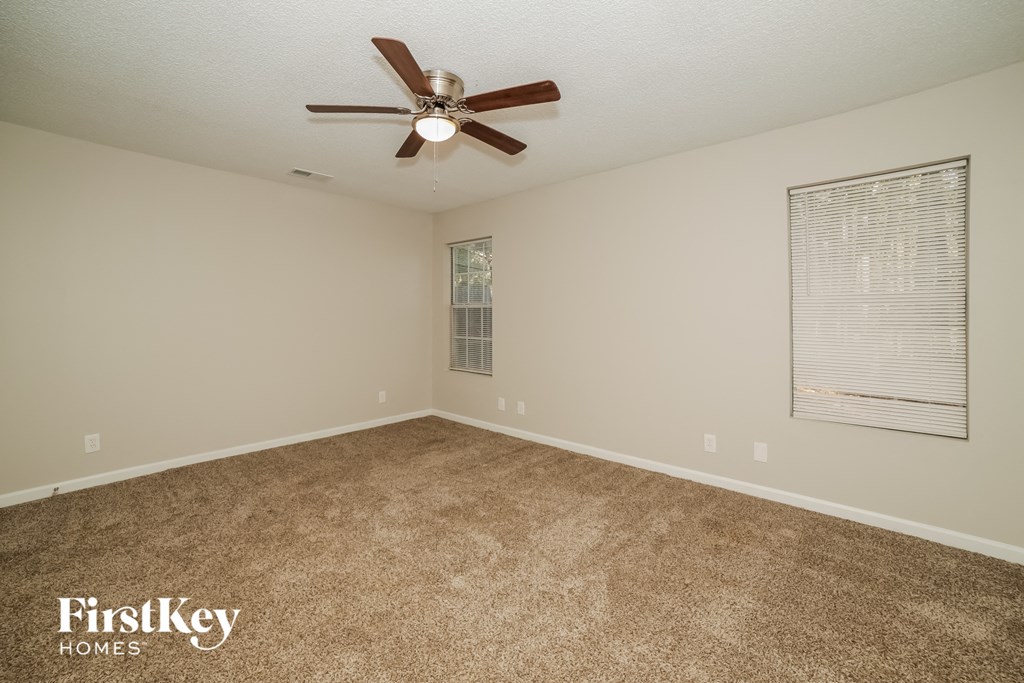 an empty living room with a ceiling fan and a window