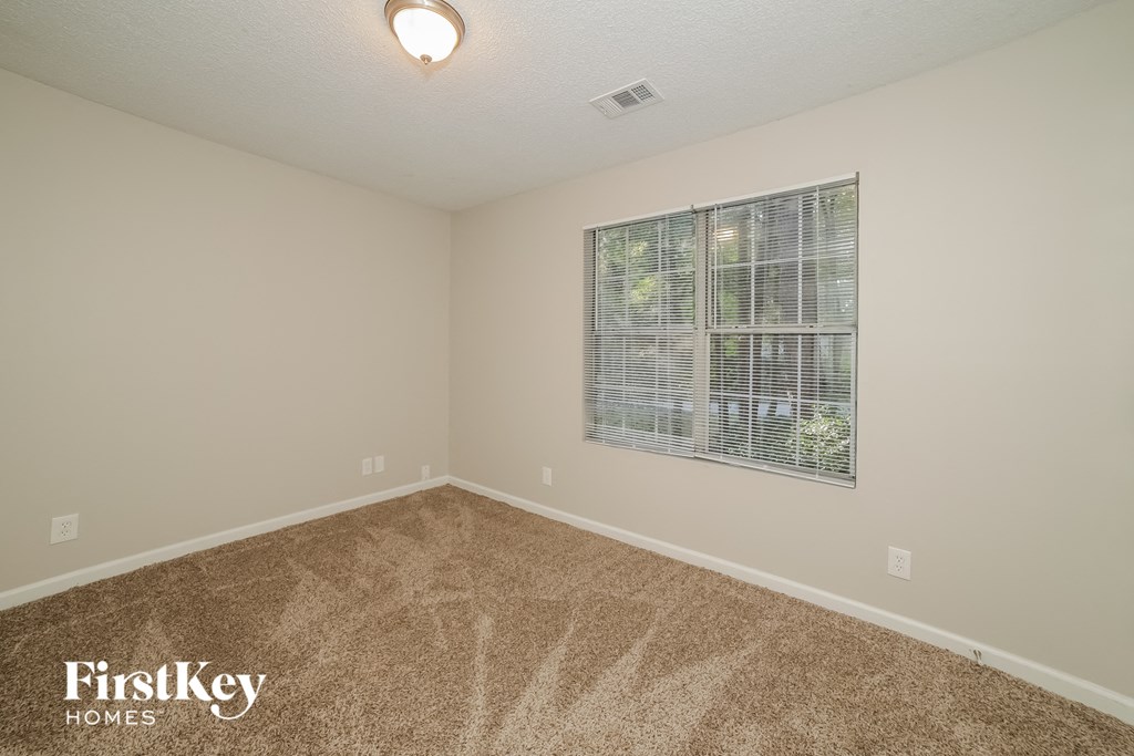 the spacious living room has carpeting and a large window