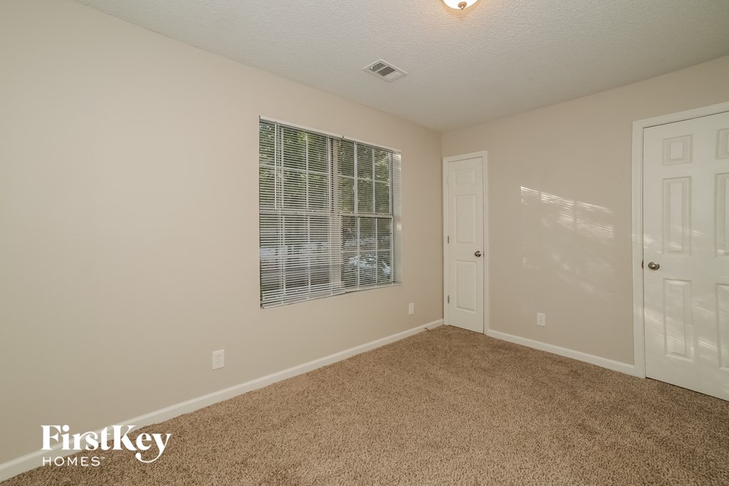 a bedroom with a window and a door and a carpeted floor