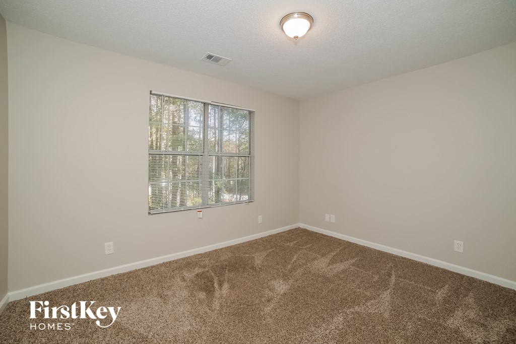 the spacious living room has carpeting and a large window