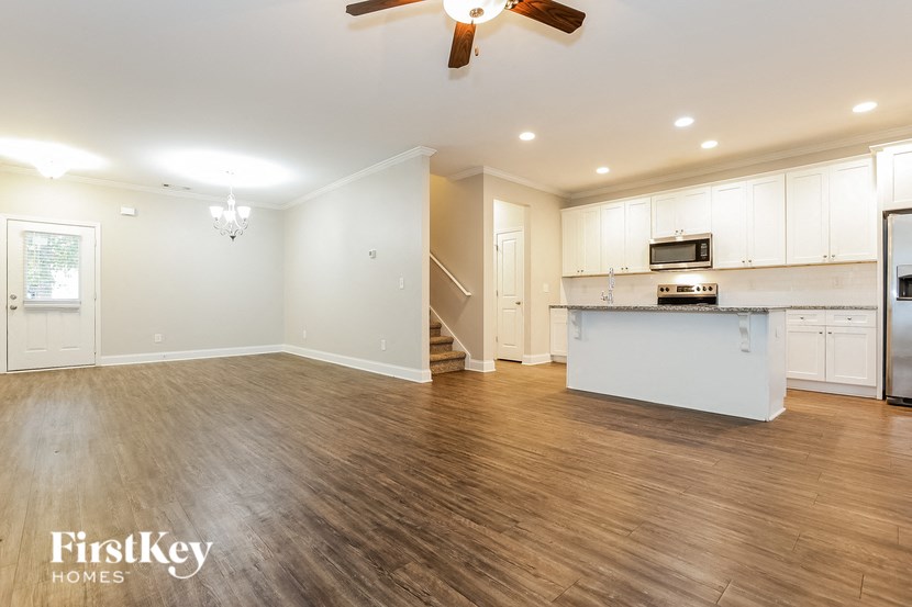 an empty kitchen and living room with white cabinets and wood floors