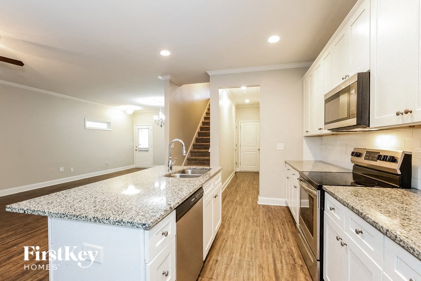 a kitchen with granite counter tops and stainless steel appliances and white cabinets