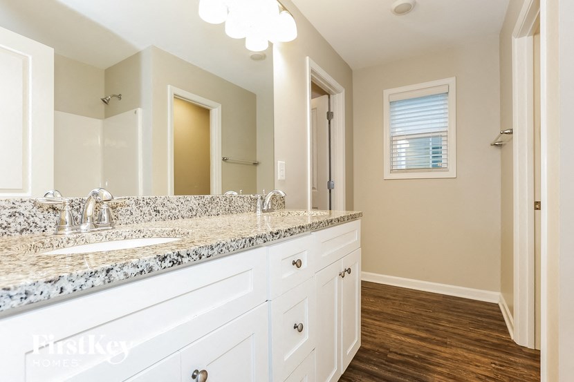 a bathroom with white cabinets and granite counter tops