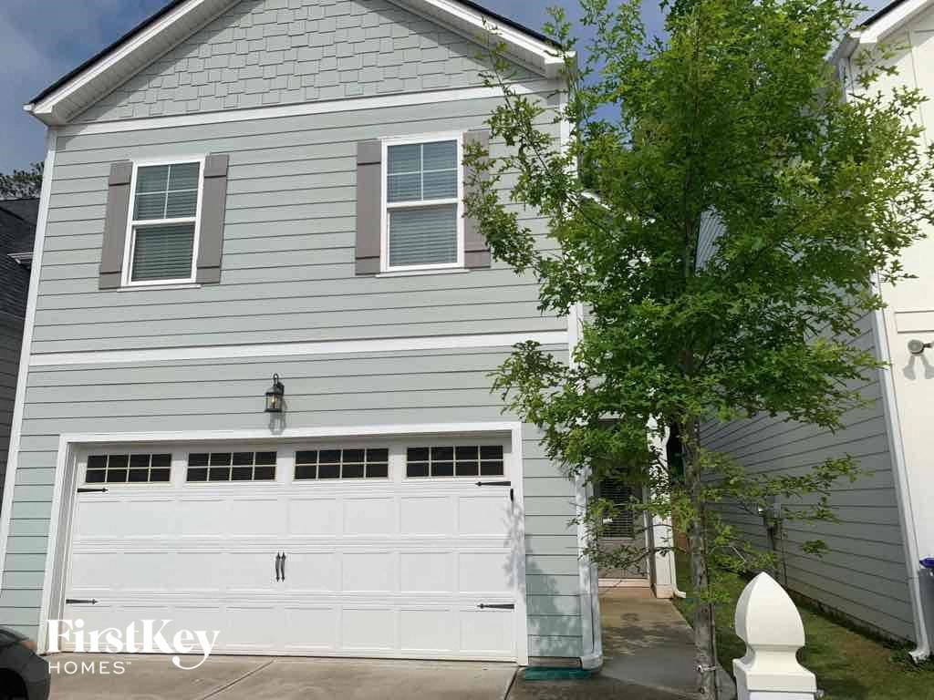 A two-story house with a garage door and a tree in front.