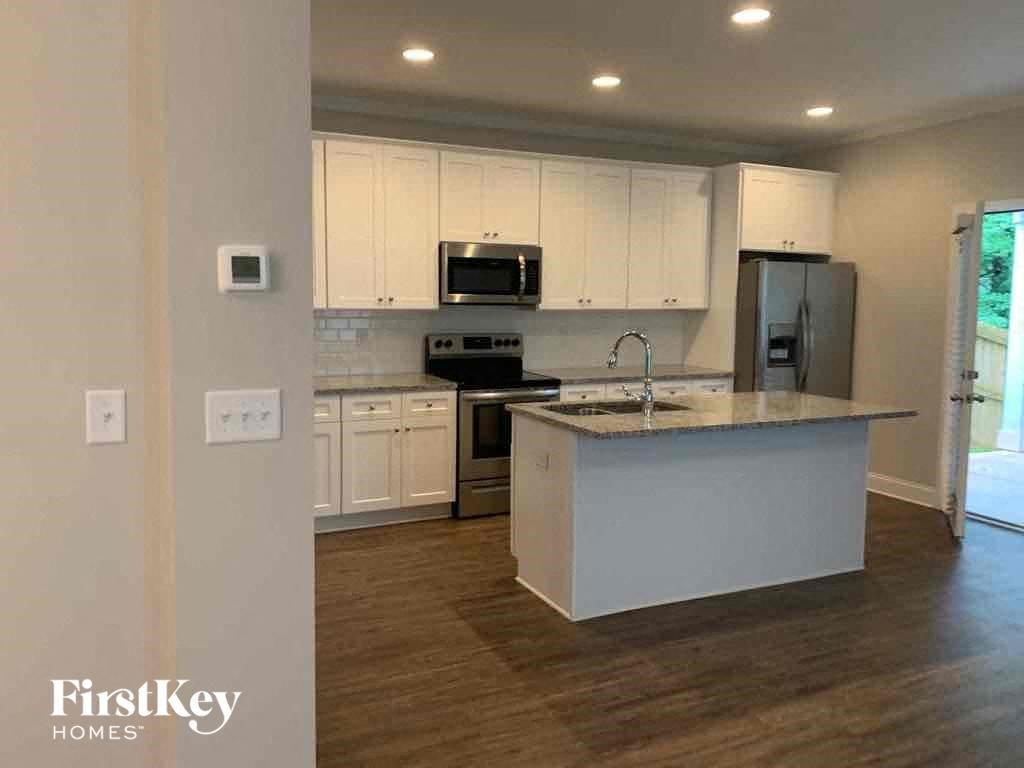 A kitchen with a white island and wooden floors.