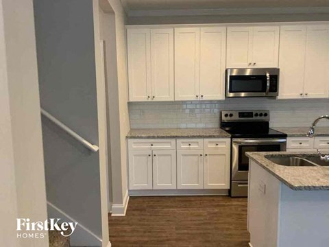 A kitchen with white cabinets and a stainless steel microwave.
