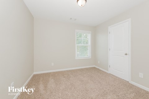 a bedroom with a carpeted floor and a white door