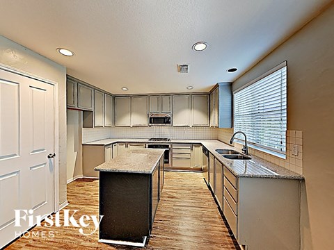 a kitchen with white cabinets and a large window