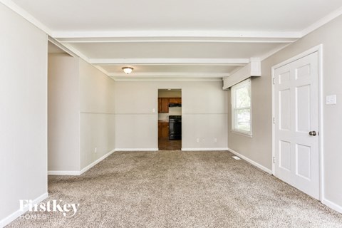 A spacious, empty room with a carpeted floor and white walls.