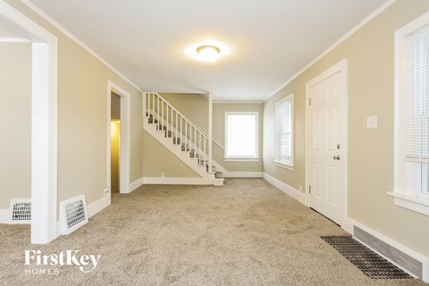 a empty living room with a staircase and a door to a hallway and a window