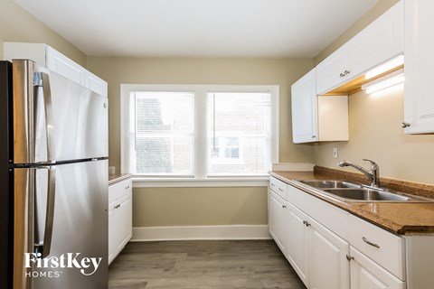 a kitchen with white cabinets and a sink and a refrigerator