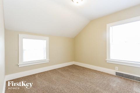 the bedroom of a home with two windows and a carpeted floor
