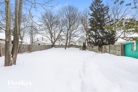 a backyard covered in snow with a green fence and trees