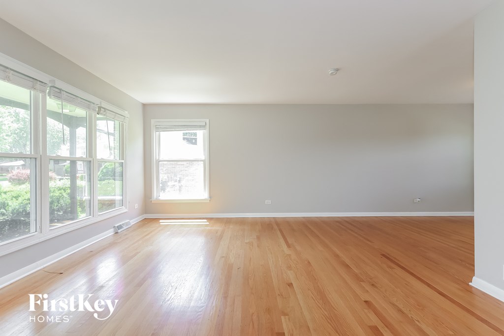 an empty living room with wood floors and large windows