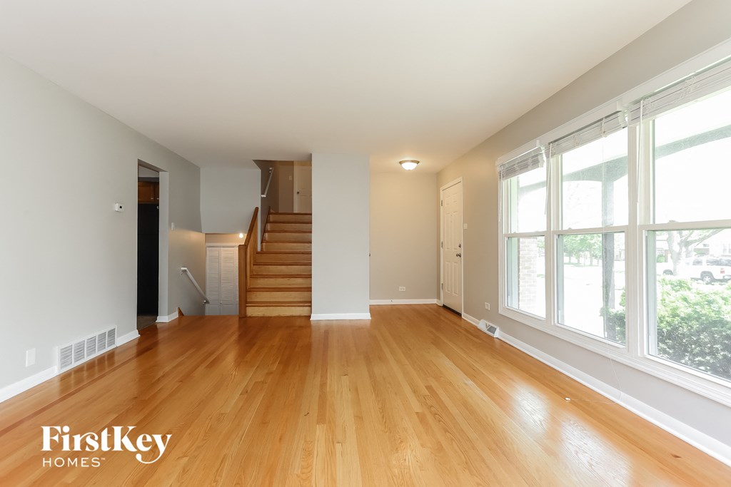 an empty living room with wood floors and large windows