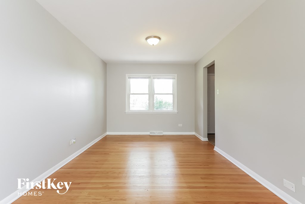a living room with white walls and wood floors and a window