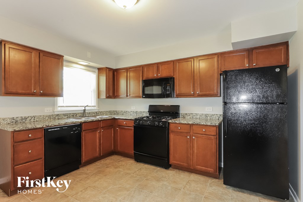 a kitchen with wood cabinets and black appliances and granite counter tops