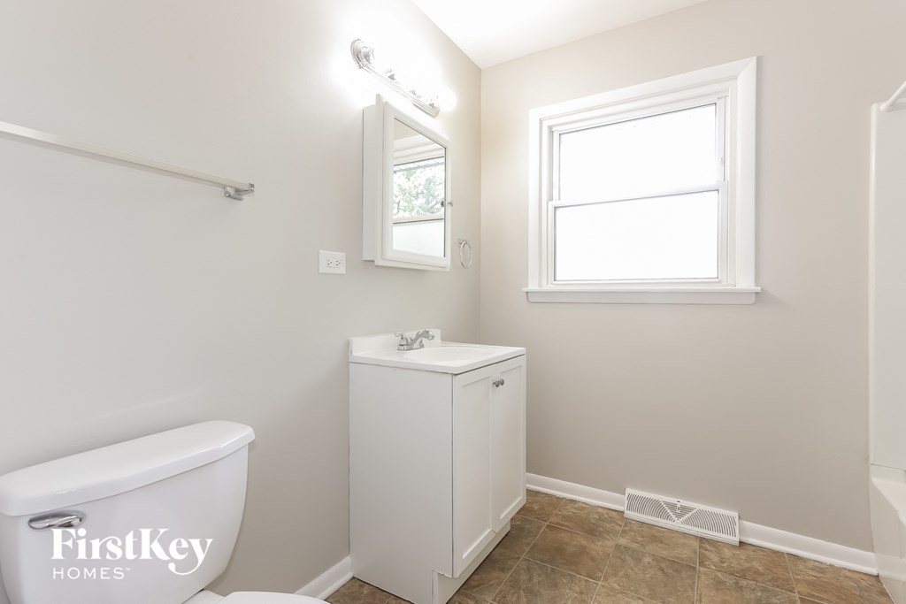 a bathroom with a toilet and a sink and a window