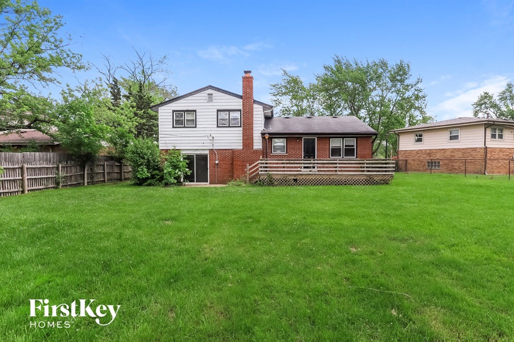 a backyard with a house and a fence and a green lawn