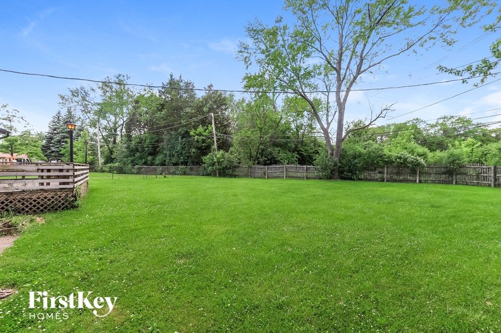 a backyard with a fence and a large grass field