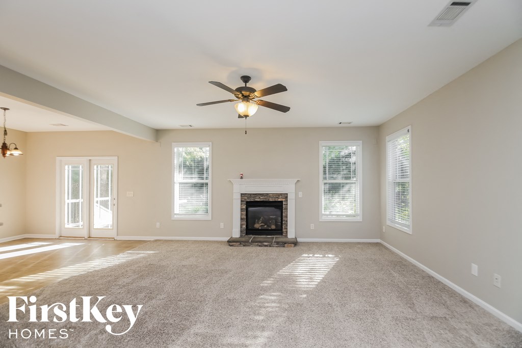 an empty living room with a fireplace and a ceiling fan