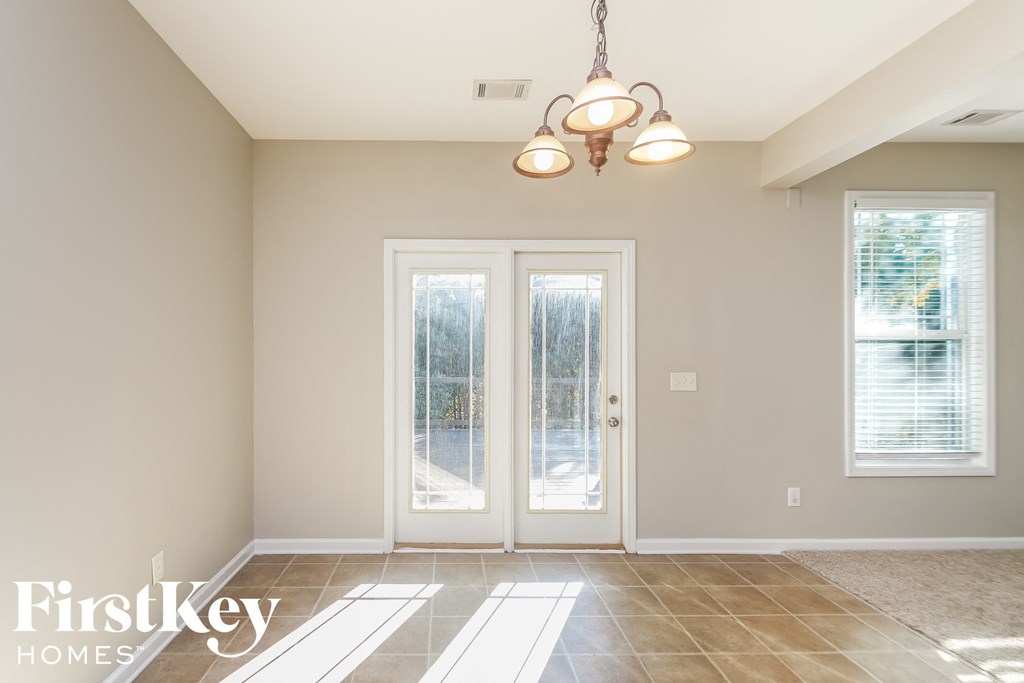an empty dining room with two glass doors and a chandelier