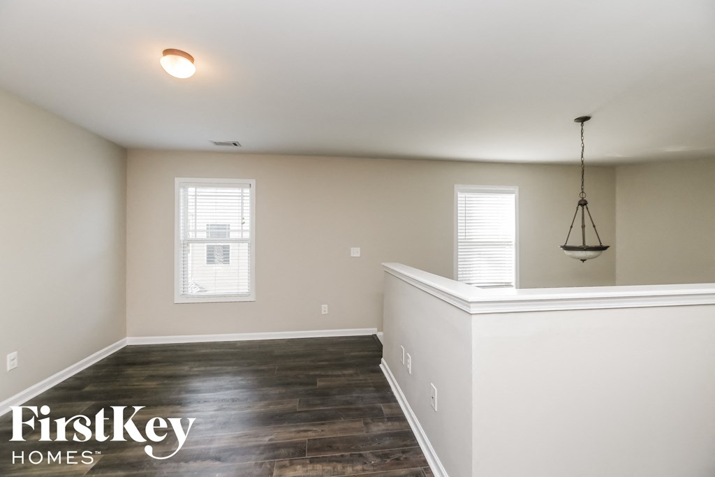 a living room with white walls and wood flooring and a chandelier