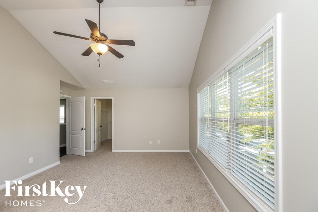 the master bedroom has a large window and a ceiling fan