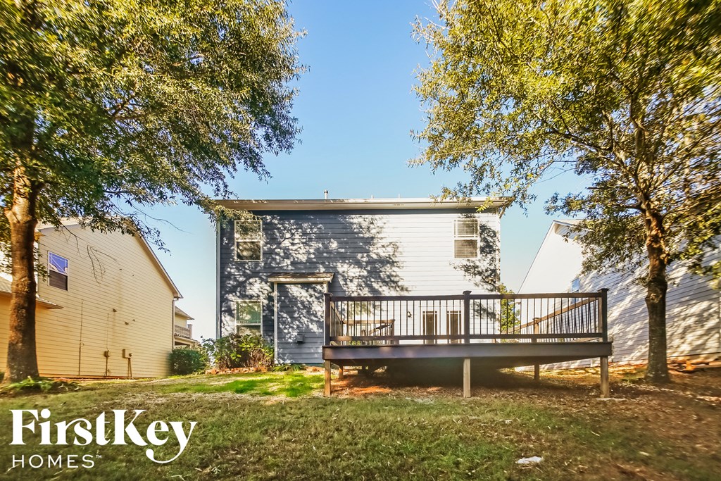 a small white house with a deck and trees