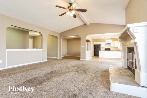 A spacious living room with a ceiling fan and a carpeted floor.