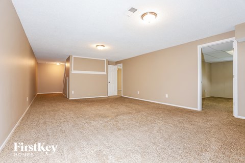 A spacious room with beige carpeting and a white ceiling.