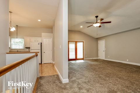 a kitchen and living room with a carpeted floor and a ceiling fan