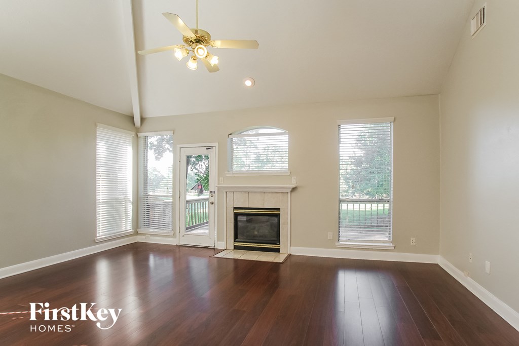 an empty living room with a fireplace and a ceiling fan