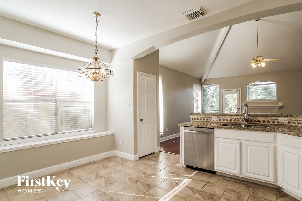 a kitchen with white cabinets and a sink and a window