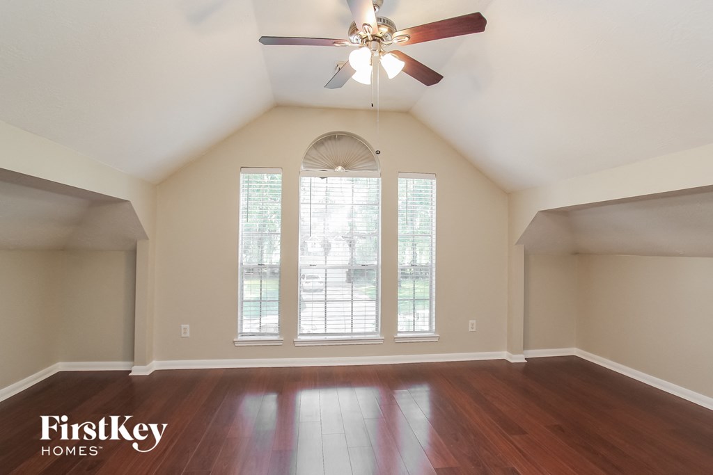 an empty living room with large windows and a ceiling fan